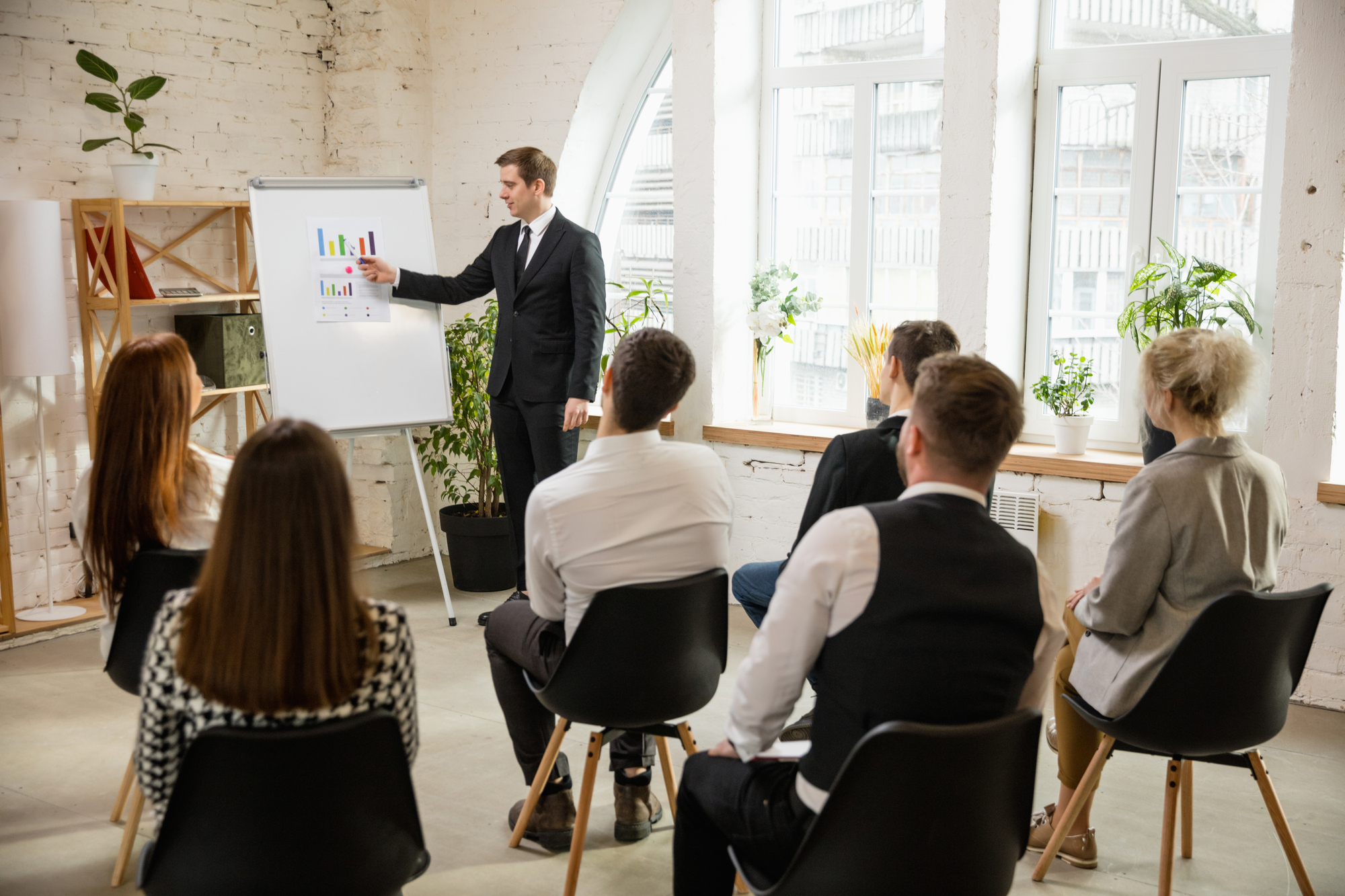Charts. Male speaker giving presentation in hall at university workshop. Audience or conference hall. Rear view of unrecognized participants. Scientific, business conference event, training. Education